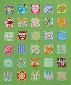 a green quilt with many different designs on the front and back, all in bright colors