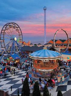 an amusement park at sunset with ferris wheel and carousel