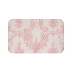 a bath mat with pink flowers and leaves on the bottom, in front of a white background