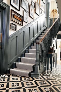 a staircase with pictures on the wall and carpeted flooring in front of it