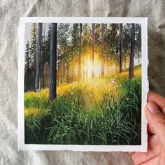 a person holding up a piece of paper with an image of trees in the background