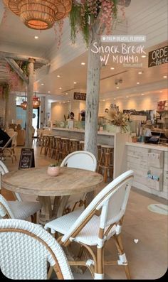 the inside of a restaurant with tables, chairs and plants hanging from the ceiling above