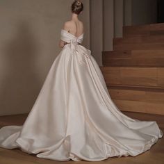 a woman in a white wedding dress standing on some stairs with her back to the camera