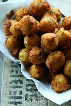 some fried food is in a white bowl on a tablecloth with a napkin and spoon