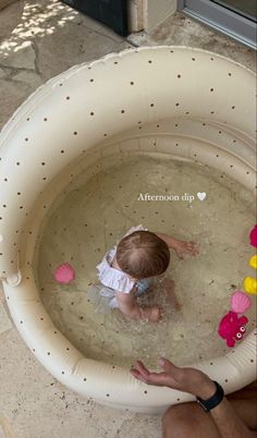 a baby sitting in an inflatable pool with flowers on the floor and water around it