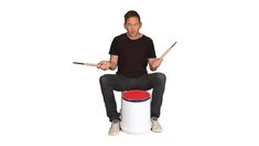 a man sitting on top of a barrel holding drums