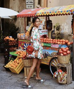 a woman standing in front of a fruit stand