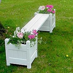 two white benches with flowers in them on the grass