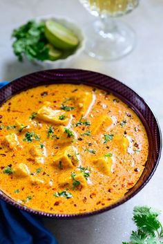 there is a bowl of soup on the table with garnishes around it