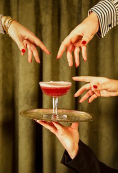 three hands reaching for a drink on a tray