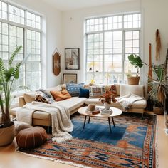 a living room filled with lots of furniture and plants on top of a wooden floor