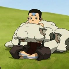 a man sitting on the ground in front of two sheep