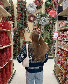 a woman is looking at christmas wreaths in a store's display case and she has her back to the camera