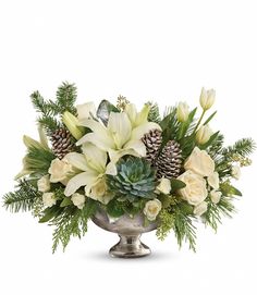 a silver vase filled with white flowers and pine cones