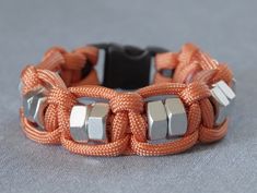 an orange bracelet with silver beads and metal clasps on a gray background, close up