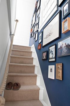 a staircase with pictures on the wall and photos hanging on the wall above it, along with shoes