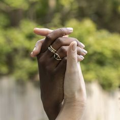 two hands holding each other with trees in the back ground behind them and one person's hand on top of another