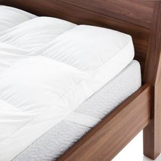 the bed frame is made up with white sheets and pillows on top of it, along with a wooden headboard