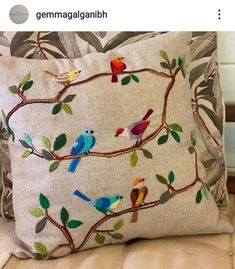 a pillow with birds on it sitting on a couch