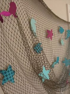 a net with blue and pink butterflies hanging from it's sides on the wall