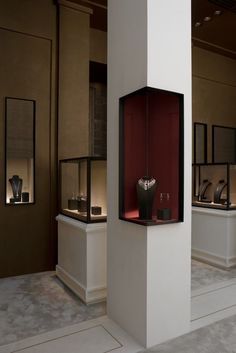 a display case with two vases in it and other items on the wall behind them