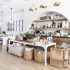 a kitchen filled with lots of white furniture and wooden shelves next to a dining room table