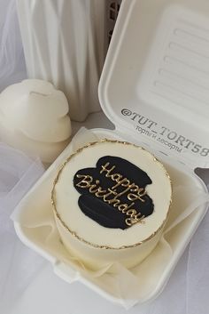 a white and black cake sitting on top of a plastic tray next to a container