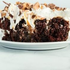 a piece of chocolate cake on a plate with white frosting and chopped walnuts