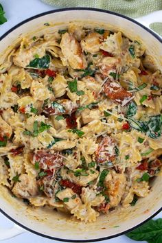 pasta with chicken, spinach and tomatoes in a pan