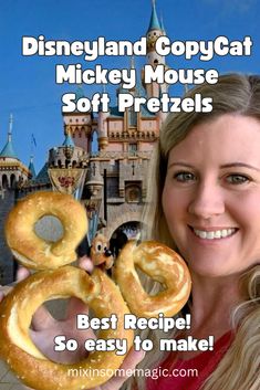 a woman holding two pretzels in front of a castle with mickey mouse on it