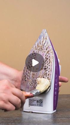 a person using an iron on top of a wooden table with a video screen showing how to use the iron