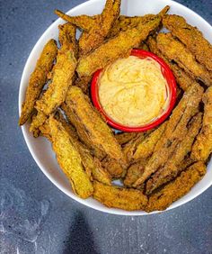 a white bowl filled with fried food on top of a blue tablecloth next to a red sauce