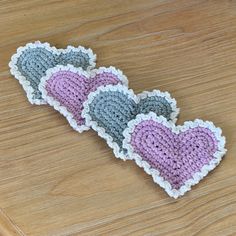 three crocheted hearts sitting on top of a wooden table