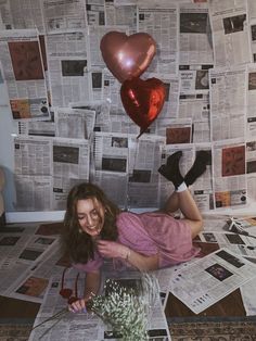 a woman laying on the floor with balloons and newspaper