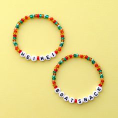 two beaded bracelets sitting on top of a yellow table next to each other