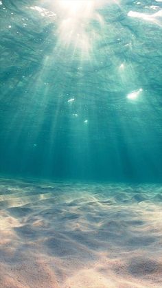 the sun shines through the water as it floats above the sandy bottom of the ocean