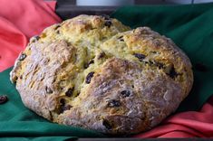 a loaf of bread sitting on top of a green and red cloth next to a cup