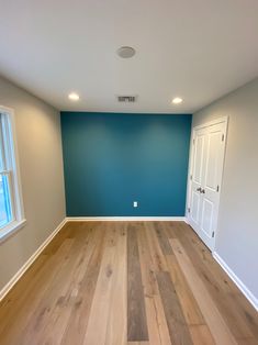 an empty room with blue walls and wood floors