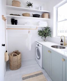 a washer and dryer in a white laundry room with shelves above the sink