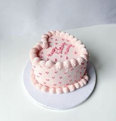 a birthday cake with pink frosting and hearts on it, sitting on a white plate