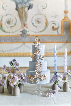 there are many small vases with flowers on the table next to each other in front of a cake