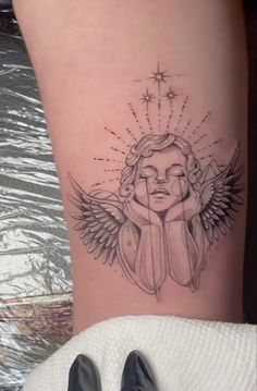 a woman's leg with an angel tattoo on the side of her thigh, which is surrounded by stars