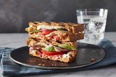 a sandwich cut in half sitting on top of a plate next to a glass of water