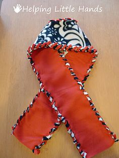 an orange and black ribbon on top of a wooden table with the words helping little hands written above it