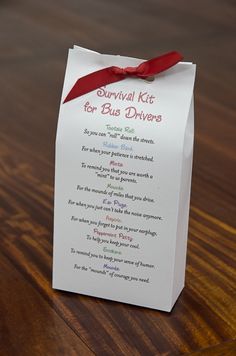 a small white box with a red ribbon on it sitting on top of a wooden table