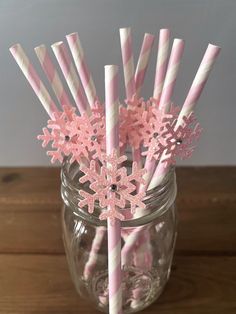 pink and white striped paper straws with snowflakes on them in a mason jar