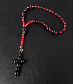 A unique one decade rosary that is shaped around the base of red and black; representing the colors of the Cardinal and the seriousness of one's pure faith and responsibility towards others. Created purely from Black Onyx, Red Corals and a gemstone black cross, the rosary is meant to accompany you during your darkest hours and to strengthen your faith. Additional Uses: When time is not a luxury of yours and yet you wish to dedicate a prayer, a one decade rosary is what you need to have at your d Red Spiritual Jewelry With Black Beads, Spiritual Red Jewelry With Black Beads, Handmade Red Rosary With Cross, Handmade Red Rosary, Handmade Red Cross Rosary, Black Rosary With 108 Beads As Gift, Handmade Black Cross Rosary Bracelet, Handmade Black Rosary Gift, Spiritual Black Rosary With 108 Beads