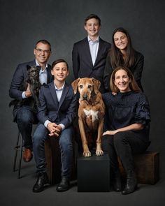 a family poses for a photo with their dog and two children in front of a dark background