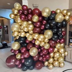 there are many balloons in the room and one is red, black, and gold