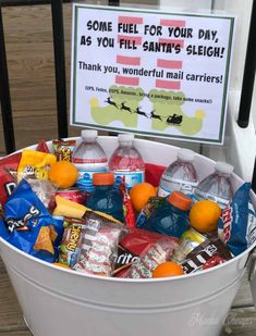 a bucket filled with lots of candy sitting on top of a wooden floor next to a sign that says some fuel for your day, as you fill santa's sleigh